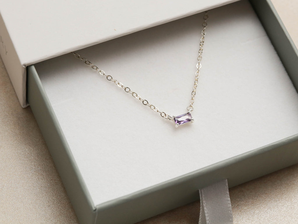 A small custom amethyst birthstone baguette necklace in a gift box.